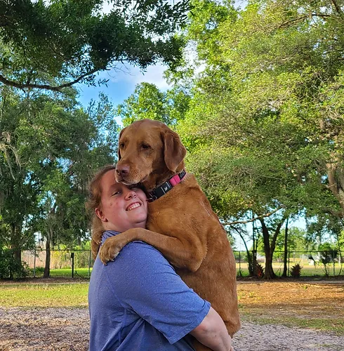 lady holding a dog at
                         park